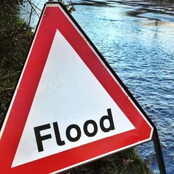 A sign reading "Flood" sits in front of a flooded street