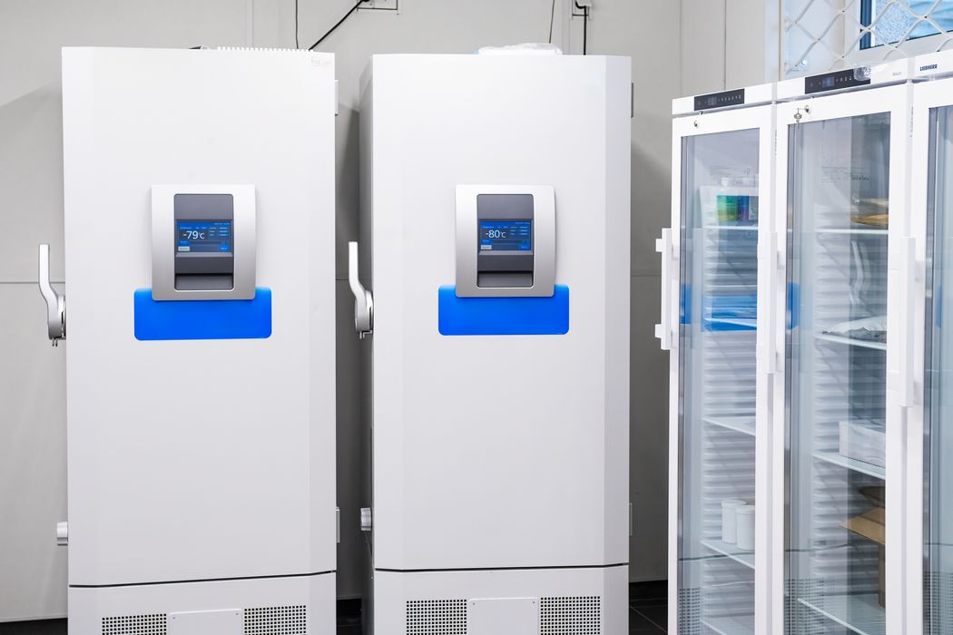 Two ultra-low temperature freezers and two refrigerators sit in the corner of a laboratory