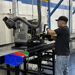 Man charging a temperature control instrument with R290 natural refrigerant on manufacturing floor.