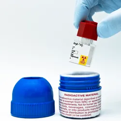 a gloved hand taking a small vail of isotope out of a shielded container illustrating the importance of Radiation Safety in Liquid Scintillation Counting