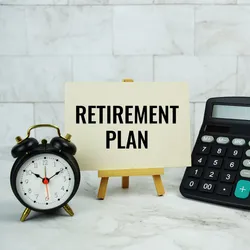 a clock, piggy bank, calculator, and small sign that reads retirement plan, items sybolic of the importance of employee retirment planning
