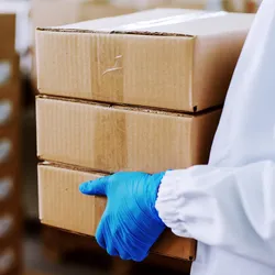 Close up of worker holding boxes and putting them on pile.