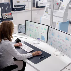Scientist analyzing real-time lab monitoring data on multiple screens in a high-tech laboratory.
