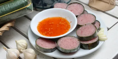 Nem Chau, Vietnemaese Fermented pork sausage sliced on a white tabletop with bowl of sauce