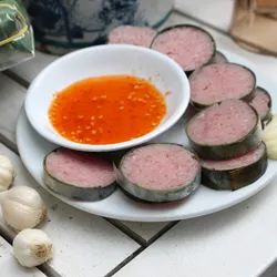 Nem Chau, Vietnemaese Fermented pork sausage sliced on a white tabletop with bowl of sauce