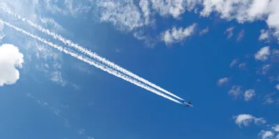 commercial aircraft flying in blue sky with white contrails behind the plane illustrating the difference between contrails and chemtrails