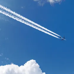 commercial aircraft flying in blue sky with white contrails behind the plane illustrating the difference between contrails and chemtrails