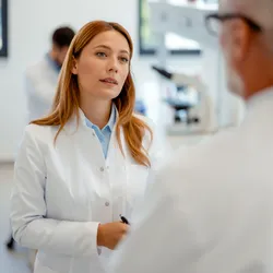 woman working in a lab being confronted by a male co-worker illustrating the concept of remote work vs in person concerning workplace discrimination