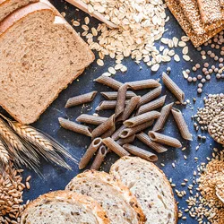 A table covered with bread, oats, pasta, and other sources of carbs