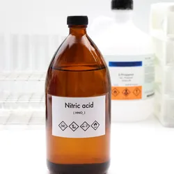 A laboratory bottle labeled "Nitric acid (HNO₃)" is prominently displayed in the foreground, with hazard symbols indicating corrosive, toxic, and flammable properties. The image reflects key themes of lab safety, root cause analysis, and the cause tree method used to investigate chemical incidents.