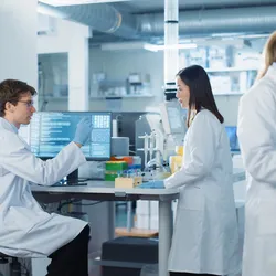 Scientists working with high-tech equipment in an automated diagnostic lab environment.