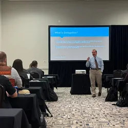 Male speaker presenting on delegation to a seated audience at the Lab Manager Leadership Summit.