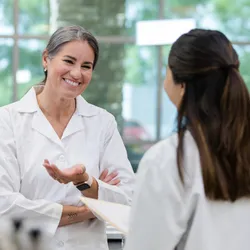 A smiling lab manager engages in a one-on-one conversation with a team member, illustrating effective lab team leadership through open communication.