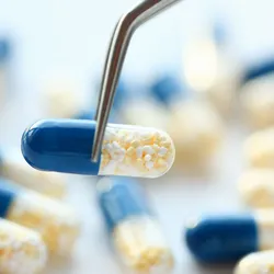 a pharmaceutical capsule being lifted with foreceps illustrating the comcept of stability testing of drigs and pharmaceuticals