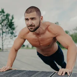 Man without shirt doing push-ups, exhibiting healthy levels of testosterone for men.