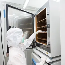 Scientist placing a cell culture inside a Co2 incubator.