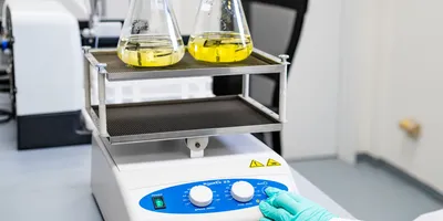 Gloved scientist operating a lab shaker.