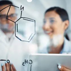 Two scientists discussing chemical structure drawn on glass in a laboratory, highlighting collaboration, lab resilience, and scientific teamwork.