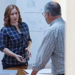 Woman discussing workplace conflict resolution with a colleague in a meeting room.