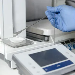 Scientist measuring a powder in an analytical balance.