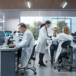 Scientists collaborating and working with lab equipment in a modern, multi-station research facility.