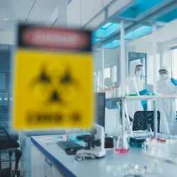 Scientists walking through a lab with a biohazard sign