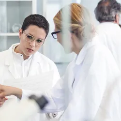 Scientists reviewing data charts during root cause analysis in a laboratory setting.