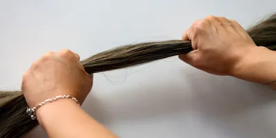 Human hands pulling a bunch of hair.
