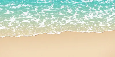 A sandy beach with water rolling against it.