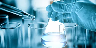 Gloved hand holding a flask of purified water beside a pipette in a laboratory setting