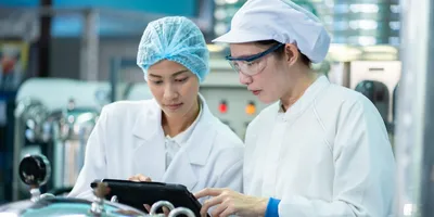Two pharmaceutical lab workers engaging in GMP training.