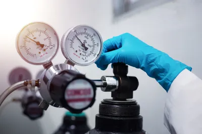 Lab technician adjusting a gas cylinder regulator—illustrates supply risk in helium-based GC workflows