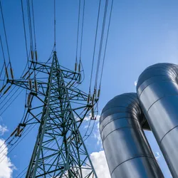 Electrical pylon next to gas pipes, symbolic of converting captured carbon to electricity.