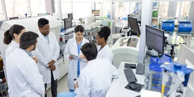Diverse medical researchers in lab coats having a collaborative discussion to prevent groupthink.