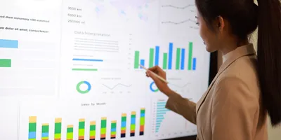 A woman looks at a large monitor displaying several charts and graphs comprised of her lab's FAIR data