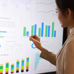 A woman looks at a large monitor displaying several charts and graphs comprised of her lab's FAIR data