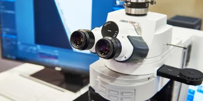 High-resolution laboratory microscope with dual eyepieces and computer display for analysis.