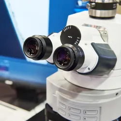 High-resolution laboratory microscope with dual eyepieces and computer display for analysis.