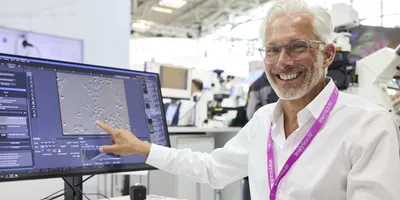 Person at an analytica trade fair pointing at scientific equipment