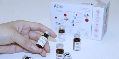 Hand holding a vial of ADC internalization reagent, a pH-sensitive red fluorescent dye that labels the human IgG Fc region. 
