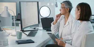 A lab manager and a scientist look at data on a computer. Standardized data is vital to scaling your lab's informatics capabilities.