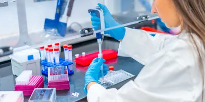 Rear view close-up of a female biologist pipetting cells in a laboratory