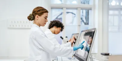 Two lab technicians working with digital data monitors