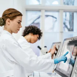Two lab technicians working with digital data monitors