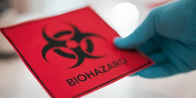 Gloved hand holding a biohazard sign