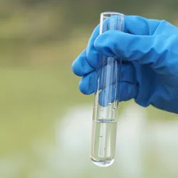 Test tube held by a gloved hand for PFAS analysis