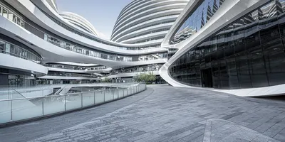Modern futuristic office complex with curved, glass-covered architecture and tiered walkways, depicting a high-tech or corporate innovation campus.