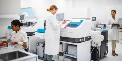 Three scientists working in a modern lab, one viewing a clipboard, representing integrating new equipment into the lab