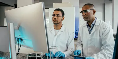 Two lab technicians engaged in on-the-job training at a computer