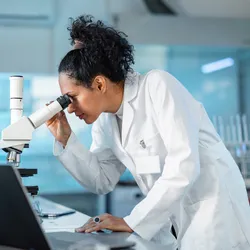 Laboratory researcher examining cells through a microscope